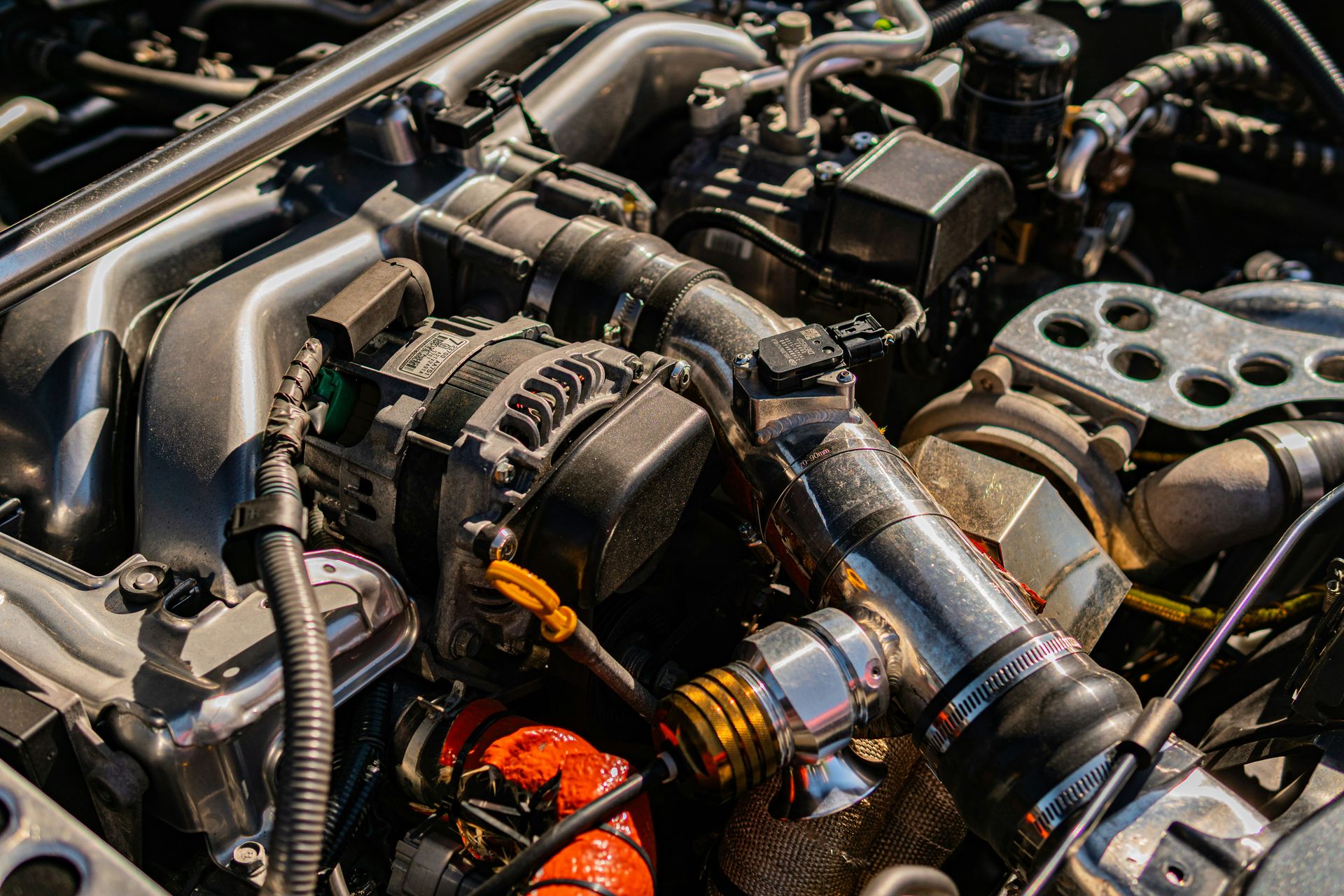 Complex car engine with various mechanical parts and hoses.