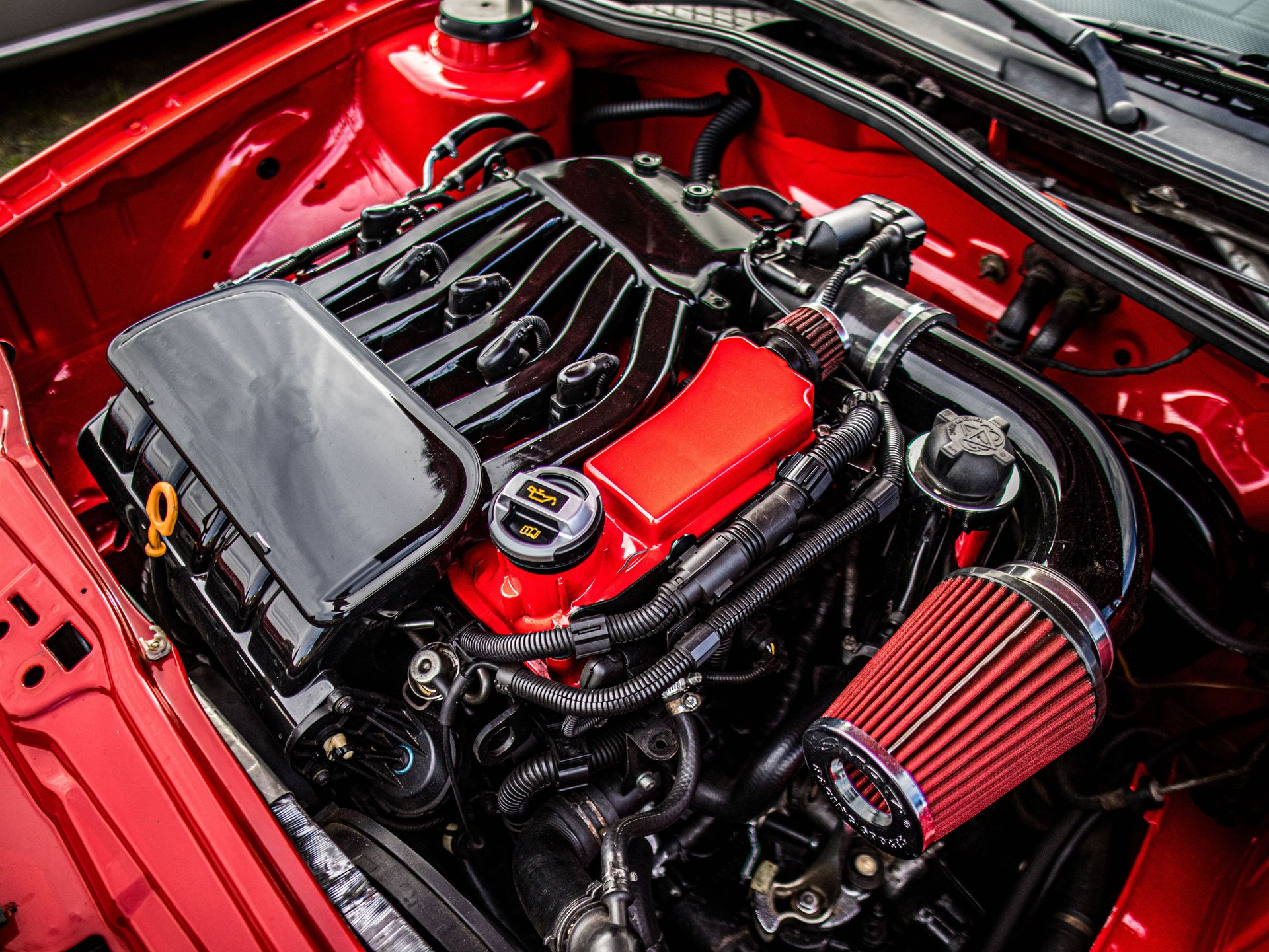 Close-up of a car engine featuring a red and black color scheme with open hood.